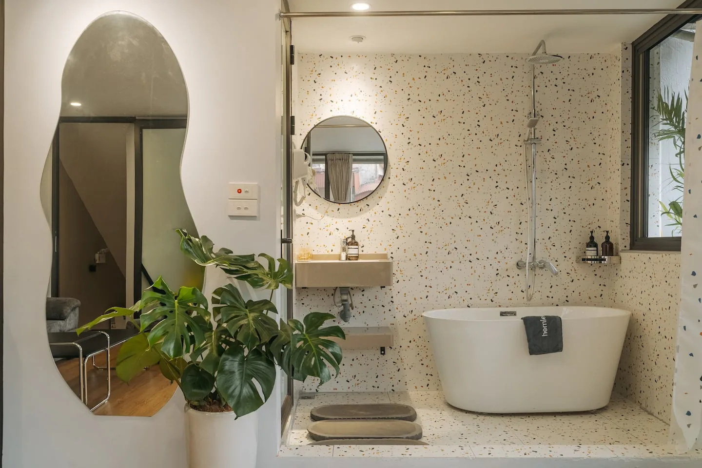 Hot tub bathroom with greenery and an arched mirror
